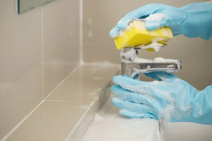 Luxury bathroom cleaning in Vancouver: cleaner scrubbing a bathroom faucet